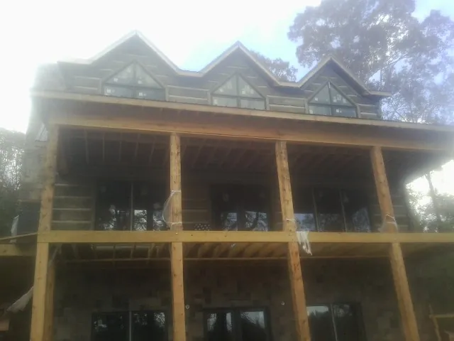 Dormers and porch framing on a large log home under construction — Roof Coating work by our crew in Vauxhall