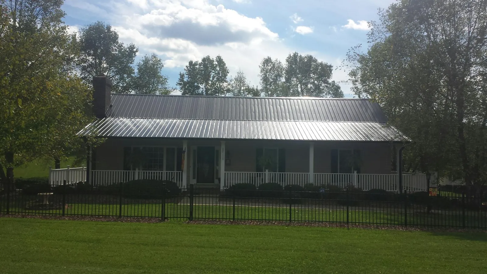 Gray metal roof on a brick ranch with a full width front porch — Gutter Guard Installation work by our crew in Vauxhall
