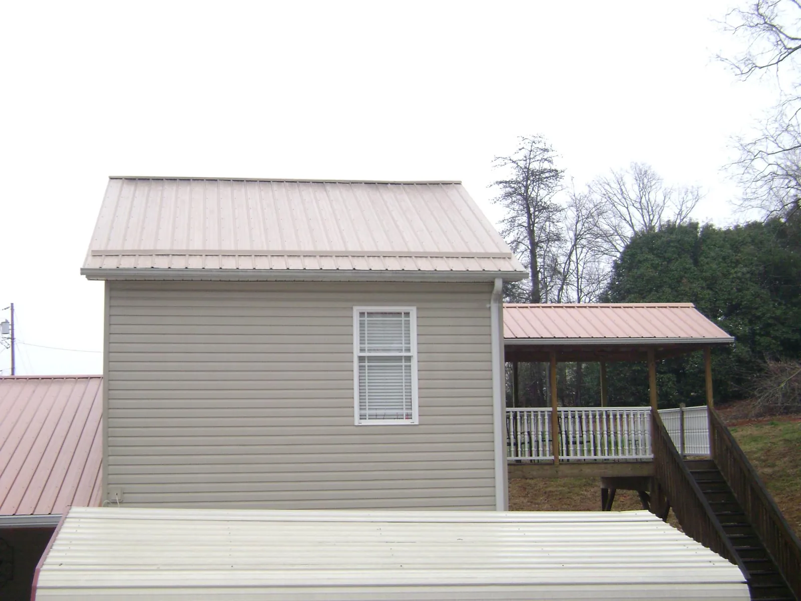 Tan metal roofs on a two story addition and attached porch, from a Roof Replacement job in Vauxhall