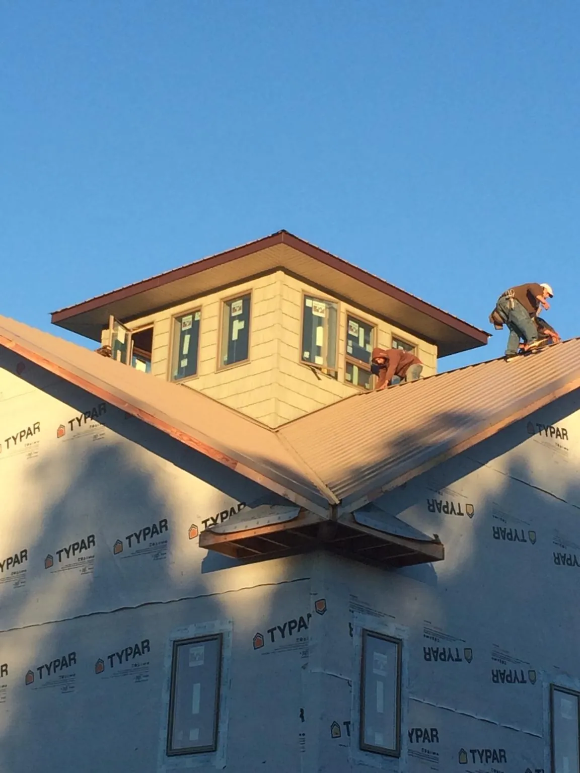 Roofers working around a rooftop cupola on a new metal roof at sunset — Roof Waterproofing in Vauxhall by Roofing Brothers